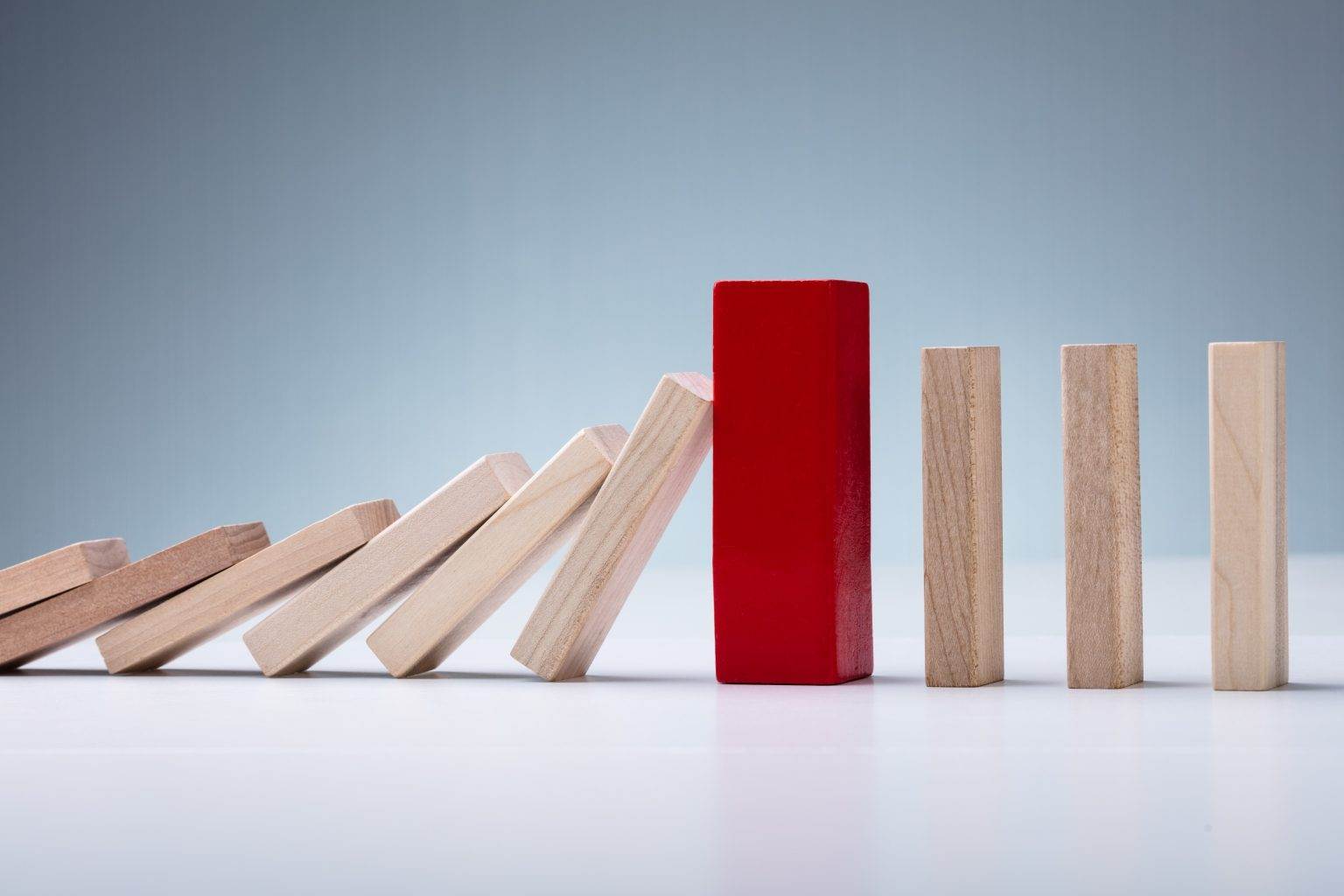 Red Wooden Block Amidst Falling And Upright Domino Pieces The Thayer 